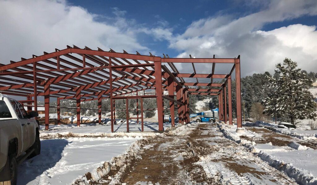 steel frame construction for barndominium in winter with snow on the ground